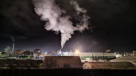 Night industrial landscape. View of large plant and snow-covered territory. Cold winter weather. Severe polar climate in the Arctic region. Industry and energy in the Far Northの写真素材