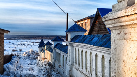 Large white old wall of the monastery on a spring or winter day or evening and a view of field with...