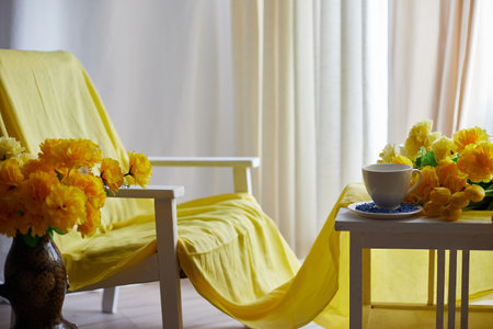 Interior in living room with armchair, table and flower by window with curtains in yellow colors. Empty location for shooting in photo studio. Concept of beauty, comfort and convenience, Partial focusの写真素材