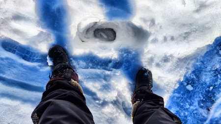 Feet of Hunter or fisherman in big warm boots on a winter day on snow. top view. A fisherman on the ice of river, lake, reservoir on a spring day with melting ice. Dangerous fishingの写真素材