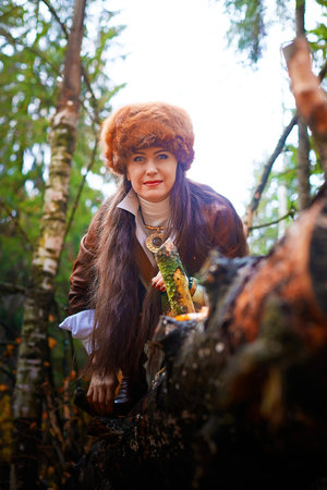 Girl in a leather jacket, a big red fox fur hat in the forest in autumn. A female model poses as a...