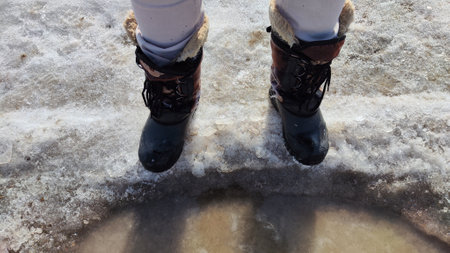 Feet of Hunter or fisherman in big warm boots on winter day on snow. top view. Fisherman on the ice...