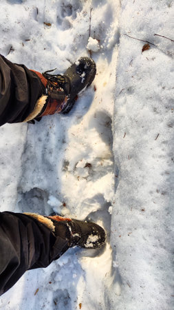 Feet of Hunter or fisherman in big warm boots on winter day on snow. top view. Fisherman on the ice...