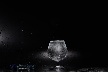 Glass cup with pure mineral water with bubbles on black backgroundの写真素材