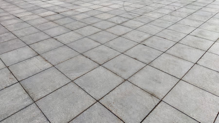 Gray tiles on sidewalk in the city outdoors. Background and texture with lines and squares of tiles....