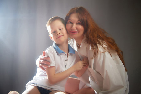 Woman with a boy. Mom with son on a white background. Family portrait with mother and boy having fun togetherの写真素材