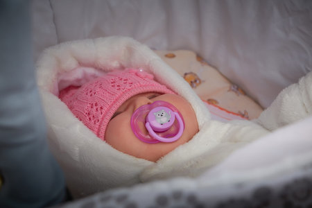 Kirov, Russia - October 23, 2022: Portrait of newborn baby in warm winter clothes in pram. Beautiful...