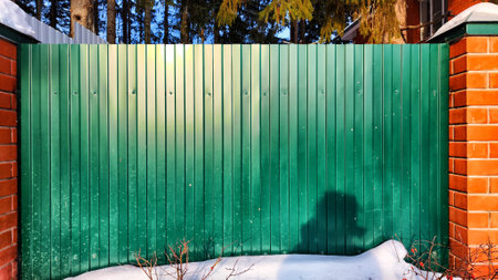 Green Metal fence with vertical picket fence and lines. Abstract background, frame, texture with place for text and copy space in winter dayの写真素材
