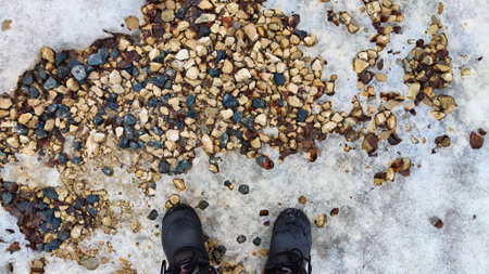 Rocks and stones laying on the ground with icy snow on cold winter day. Abstract Background, texture and frame for place for text and copy spaceの写真素材