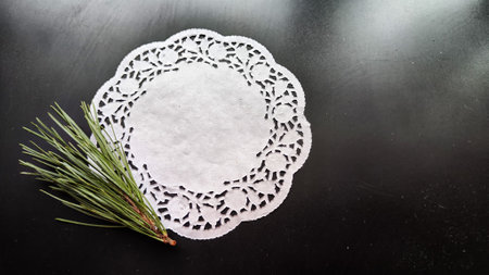 Black frame, white round napkin, green pine branch on background with reflections and sparkle of...