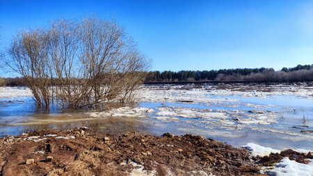 Spring landscape with water and ice on river and blue sky in background in sunny day. Ice drift and flood on river with sunの写真素材