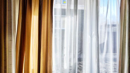 Window with transparent white tulle beige curtains. Background and texture with fabric. Copy space...
