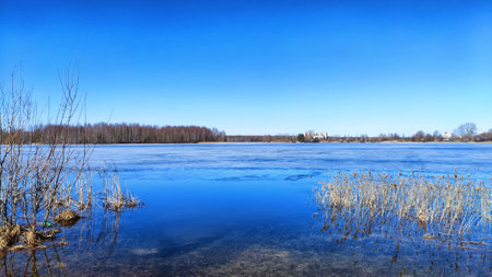 Landscape with a lake covered with ice before the start of melting and ice drift on spring day with...