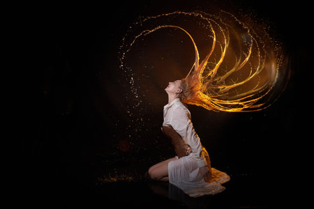 Beautiful sexy skinny girl and her flying hair in dark hall with splashes of water. Female Model blonde woman posing with water on a black background in the studioの写真素材