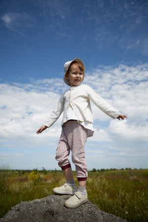 Portrait of little girl with Asian eyes in a meadow or field with grass and flowers on a sunny summer dayの写真素材