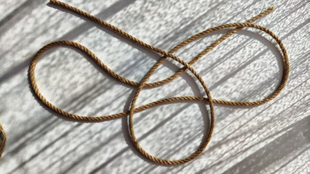 Jute twisted rope lying on a white surface with shadows from the sun. Abstract background, texture,...