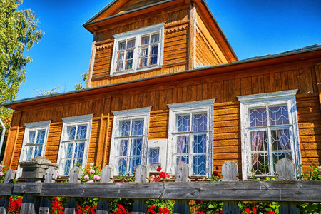 An old wooden rural house in countryside village on a sunny summer or spring day and greenery with trees and grass arroundの写真素材