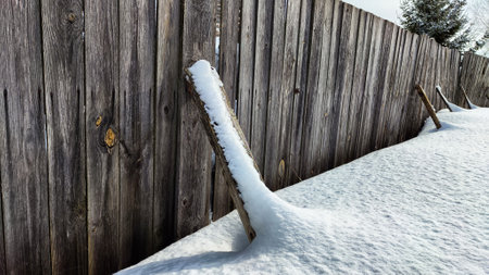 Fence made of wooden slats and snow on a winter day. Location, Background, texture, copy of space, frame as graphic resourceの写真素材