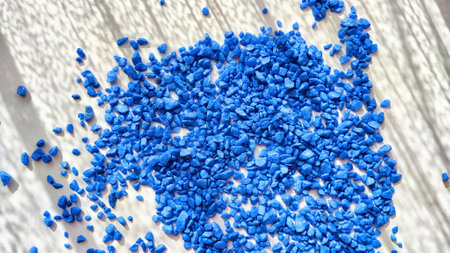 Blue painted small pebble on the surface of the table under sunlight. Abstract background, texture, frame, and copy space. Supplies for crafting and handmade.の写真素材