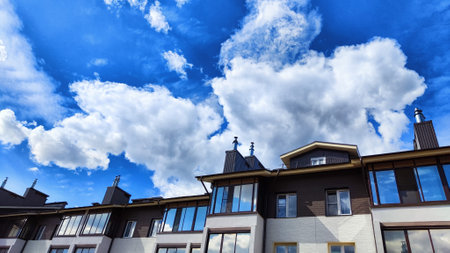 Beautiful blue sky with white cumulus clouds over village or town with houses on sunny spring, summer or autumn day. Urban landscape with nature and landscape. Background, wallpaper and copy spaceの写真素材