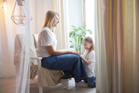 Happy loving family with mother and daughter in living room. Woman mom and small child girl playing and having convercation inside of the homeの写真素材