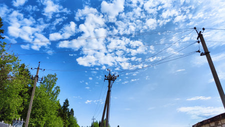 Closeup of old power poles on clear summer day. Old high voltage electric pole with wires and blue sky with clouuds on backgroundの写真素材