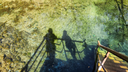 Shadows of several people on water on sunny day. Tourists on a journey. The concept of freedom in travel. Partially blurred focusの写真素材