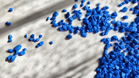 Blue painted small pebble on the surface of the table under sunlight. Abstract background, texture,...