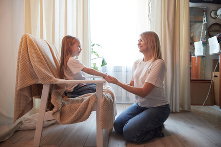 Happy loving family with mother and daughter in living room. Woman mom and small child girl playing and having convercation inside of the homeの写真素材