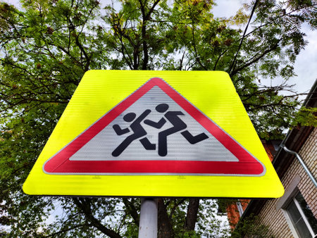 Caution Children Road Sign. Red triangle on a yellow background with black figures of running people. traffic rulesの写真素材