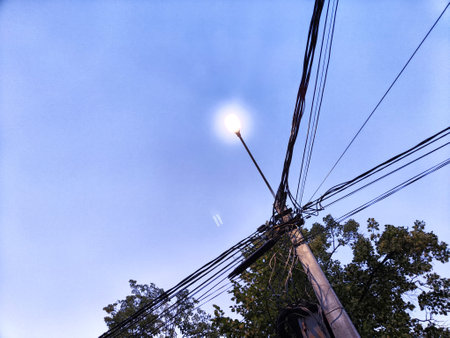 A pole with lantern and a lot of wires against the background of the evening or night sky. Lighting and power line technologiesの写真素材