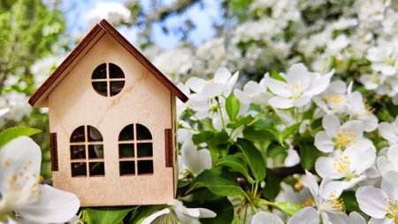 miniature toy house in apple flowers close up, spring natural background. symbol of family. mortgage, construction, rental, property concept. Eco friendly home. soft selective focus. copy spaceの写真素材
