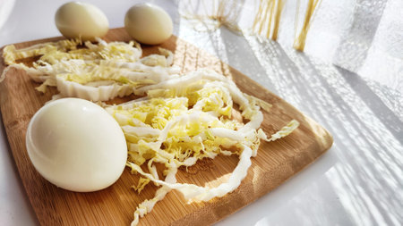 Chopped Peking cabbage and peeled eggs on cutting board as background. Cooking a healthy...