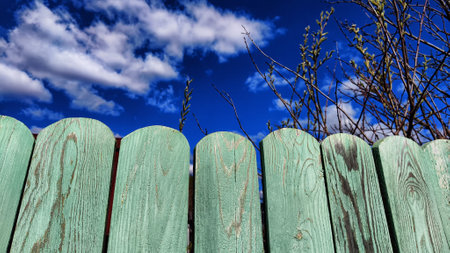 Old wooden planks in fence and blue sky with white clouds. background and texture. Abstract frame and copy space. Ancient Wooden rustic rural fence and nature landscapeの写真素材