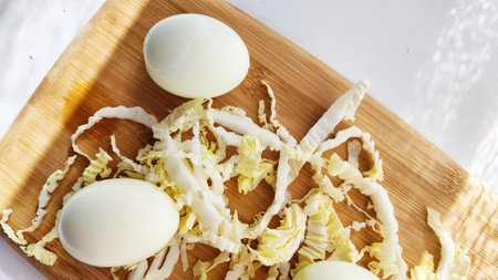 Chopped Peking cabbage and peeled eggs on cutting board as background. Cooking a healthy eco-friendly salad from natural products. Copy space and place for textの写真素材