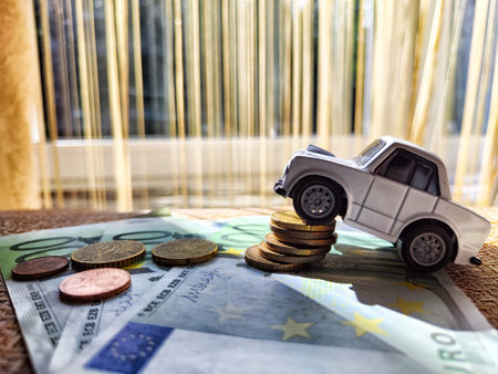 Little toy white car and euro money. Concept of the expensiveness of buying new car, affordability of buying an old car. The necessity of spending money on transportation. Cost of traveling by carの写真素材