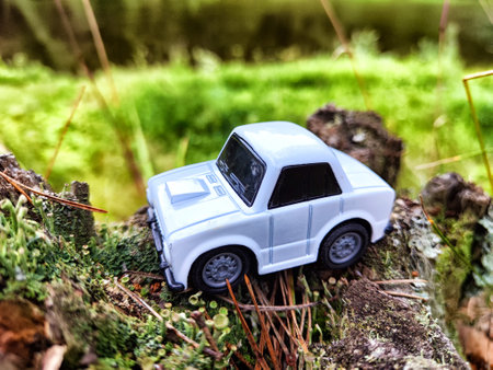 Small white toy vintage car in nature. Concept of traveling by car in forest landscape. Nostalgia for the pastの写真素材
