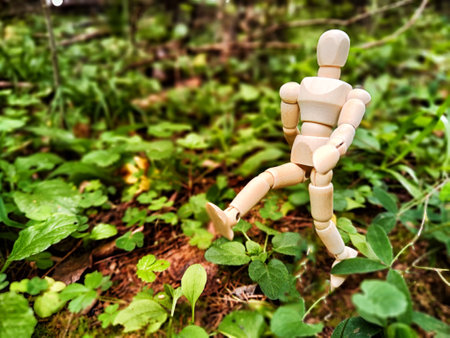 Wooden toy mannequin in forest among grass and trees in summer, autumn, spring. The concept of...
