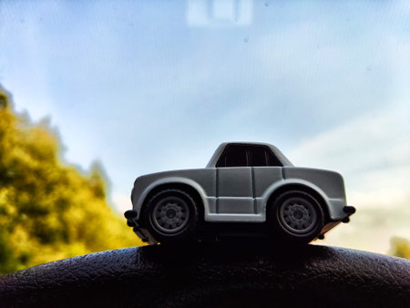 Small white toy car on background of side mirror of real big caron and nature landscape. Concept of travel and adventure by car. Freedom of movement on your own transport. Blur and partial focusの写真素材