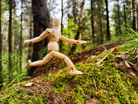 Wooden toy mannequin in forest among grass and trees in summer, autumn, spring. The concept of...