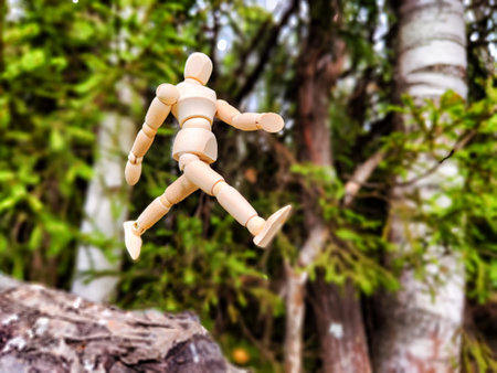 Wooden toy mannequin in forest among grass and trees in summer, autumn, spring. The concept of outdoor recreation and hiking. Healthy lifestyle. Earth Day. Save planet concept. Partial focus, blurの写真素材
