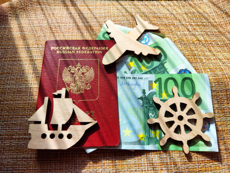 Wooden figurines, Russian passport, Euro banknotes. Concept of traveling and payment. Conflict of Russia and Ukraine, Increase in cost of sea travel, tours, flights, hotels. Price of trip to the seaの写真素材