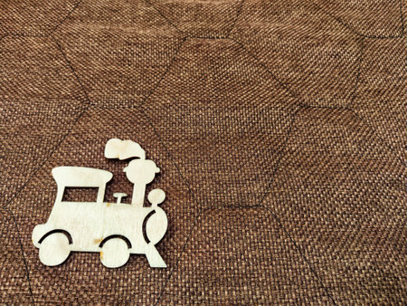 Small wooden train or locomotive on brown fabric background. Concept of travel. Background, texture,...
