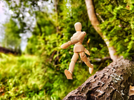 Wooden toy mannequin in forest among grass and trees in summer, autumn, spring. The concept of outdoor recreation and hiking. Healthy lifestyle. Earth Day. Save planet concept. Partial focus, blurの写真素材