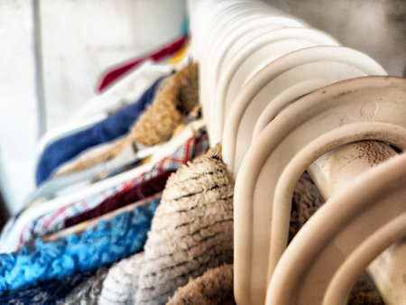 Hangers with a variety of clothes on white rack. Home storage of clothes. Clutter. Littery....