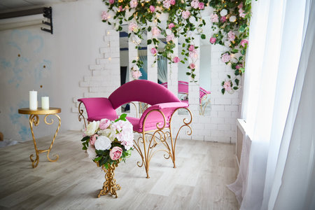 Beautiful interior with a red armchair, couch or sofa and flowers on the front and background. Bright location and a hall for a photo shootの写真素材
