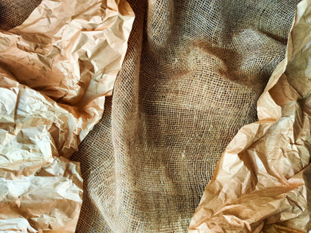 Heavily crumpled textured kraft paper in sunlight and with shadow. Abstract background, texture, frame, place for text and copy spaceの写真素材