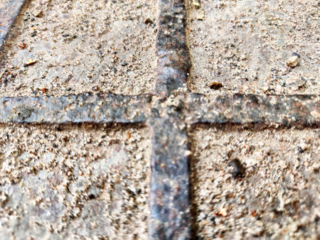 Squares in a metal grid lying on concrete, pebbles, earth. The old sidewalk or wall. Pattern of metal rods. Background, texture, frame, copy spaceの写真素材