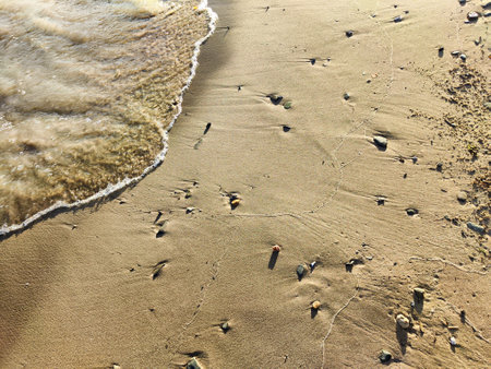 Yellow sand, pebbles and a transparent wave as a background, texture. Abstract pattern, place for text and copy spaceの写真素材