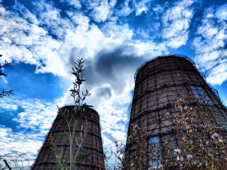 Big tower of CHPP close-up. White steam from wide pipe of CHP and blue sky. Industrial background. Huge pipes of thermal power plant produce steam for electric power. Strategically important objectの写真素材